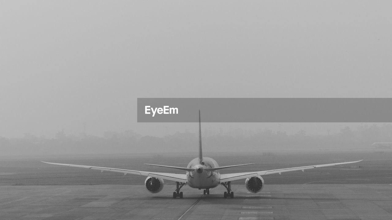 AIRPLANE FLYING OVER RUNWAY AGAINST SKY