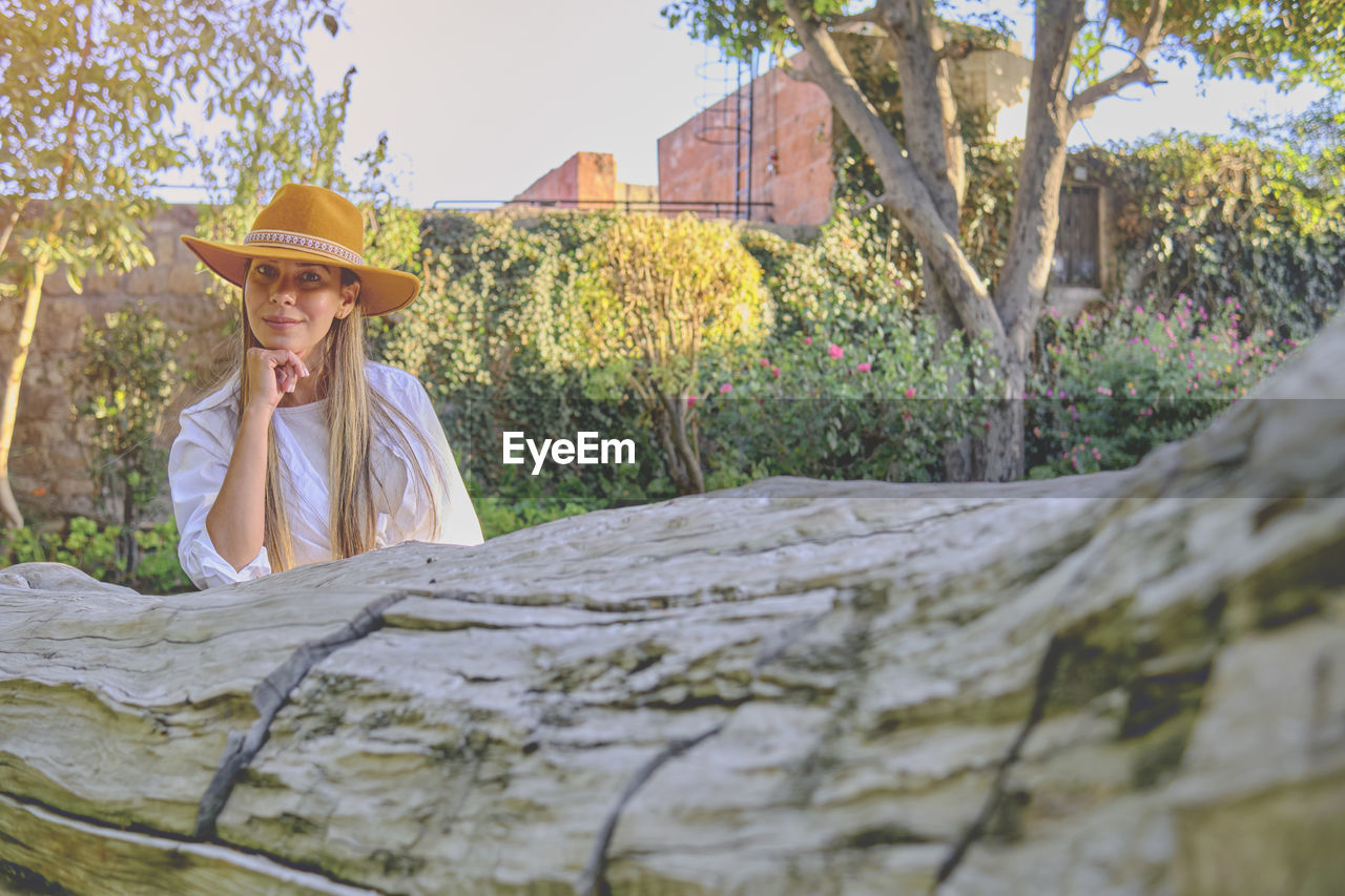 Side view of woman sitting on tree trunk
