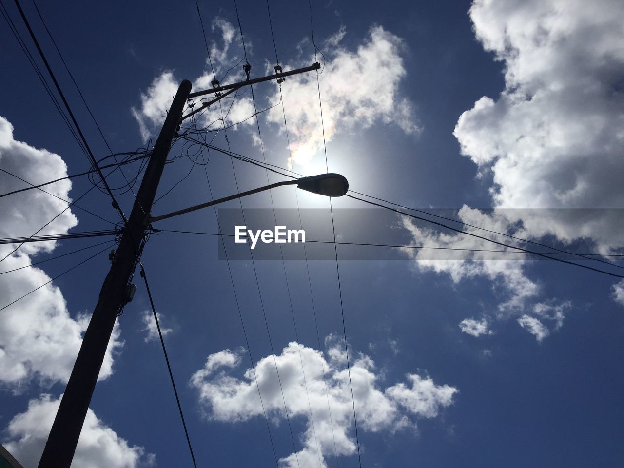 LOW ANGLE VIEW OF BIRDS FLYING OVER CABLES AGAINST SKY