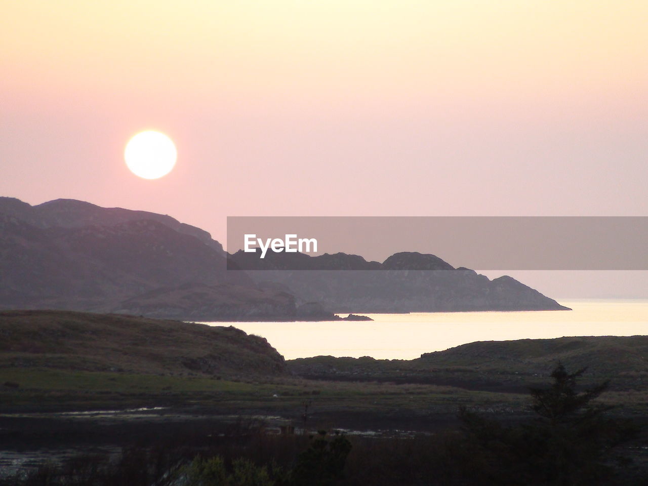 Scenic view of sunset over hills and sea