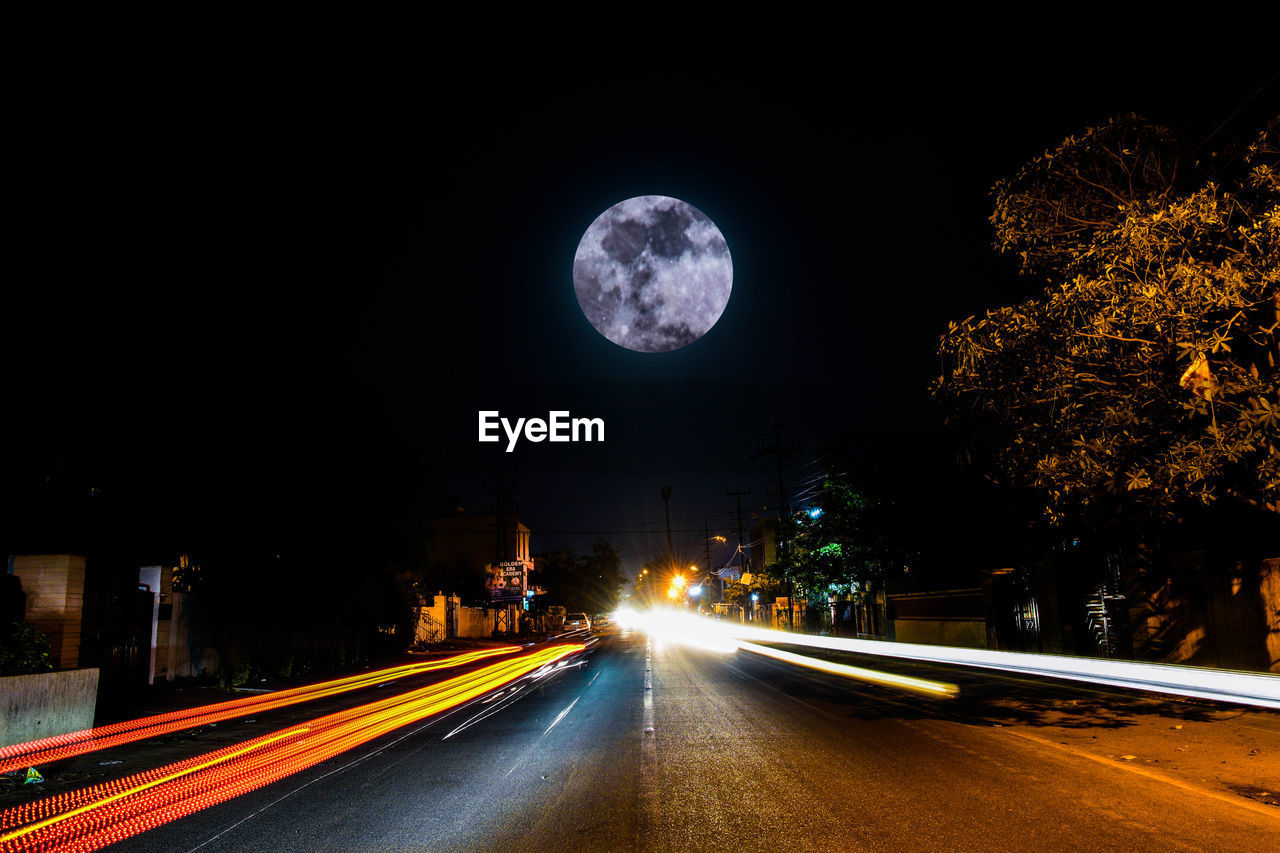 VIEW OF ILLUMINATED ROAD AGAINST SKY AT NIGHT