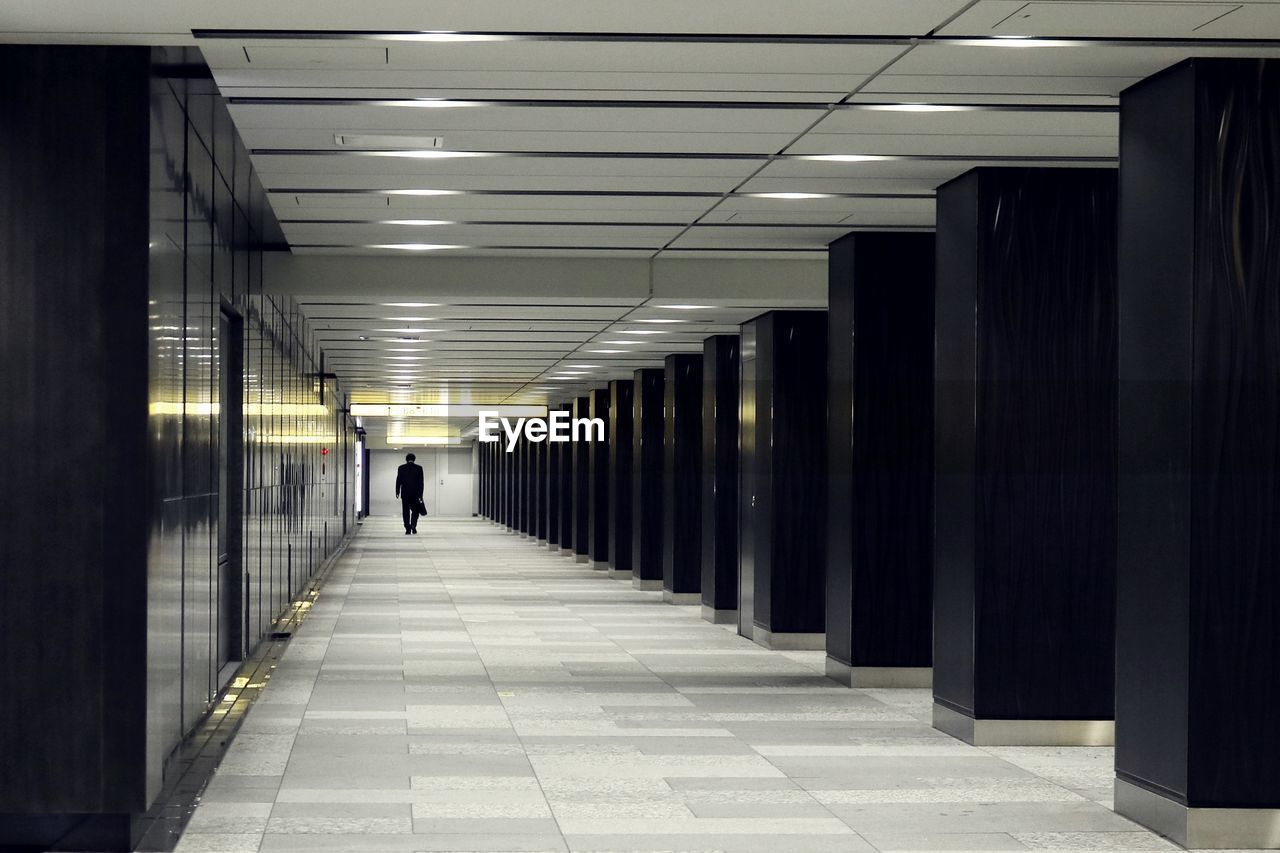 Rear view of man walking in corridor of building