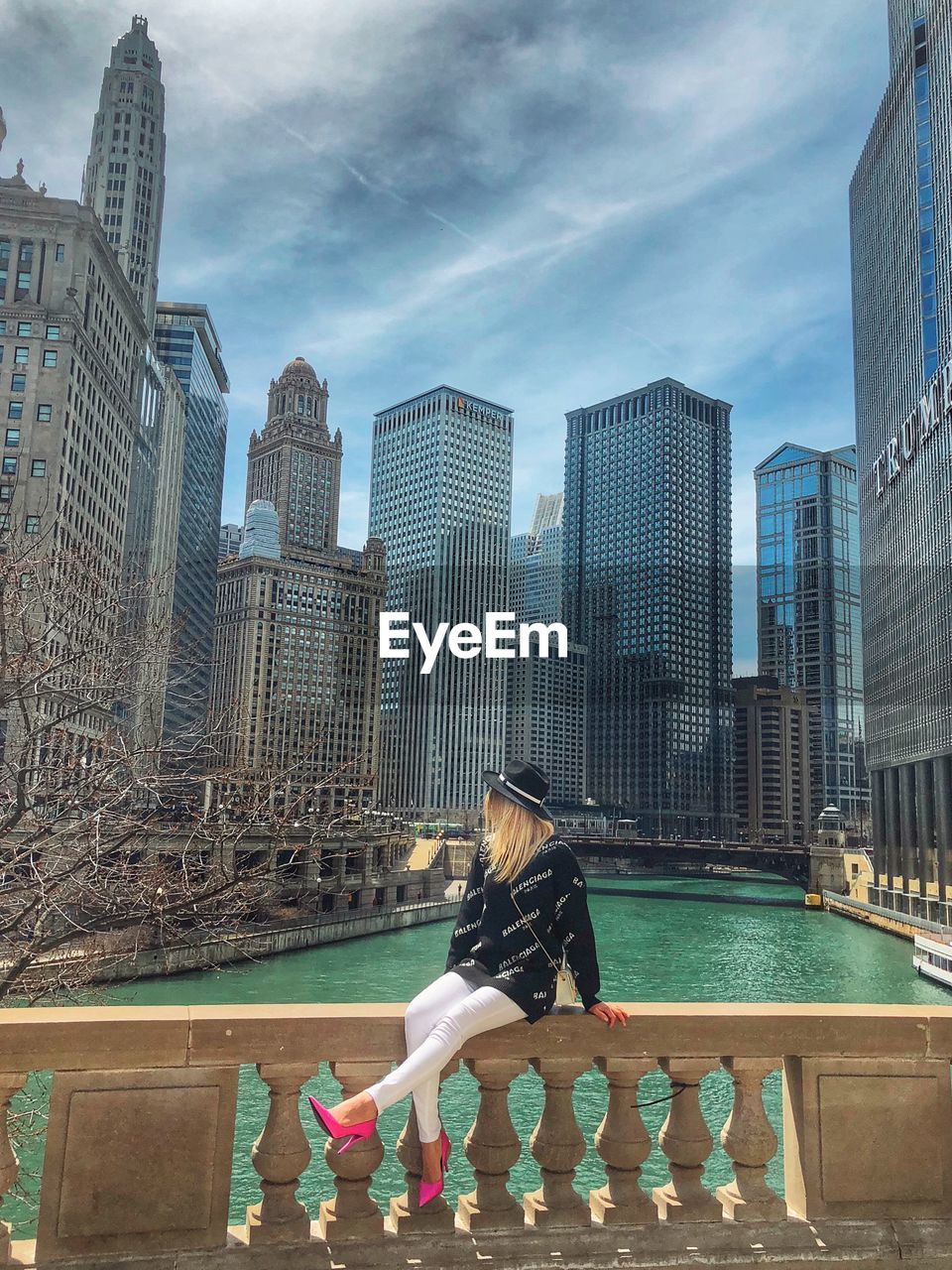 WOMAN IN SWIMMING POOL AGAINST MODERN BUILDINGS IN CITY