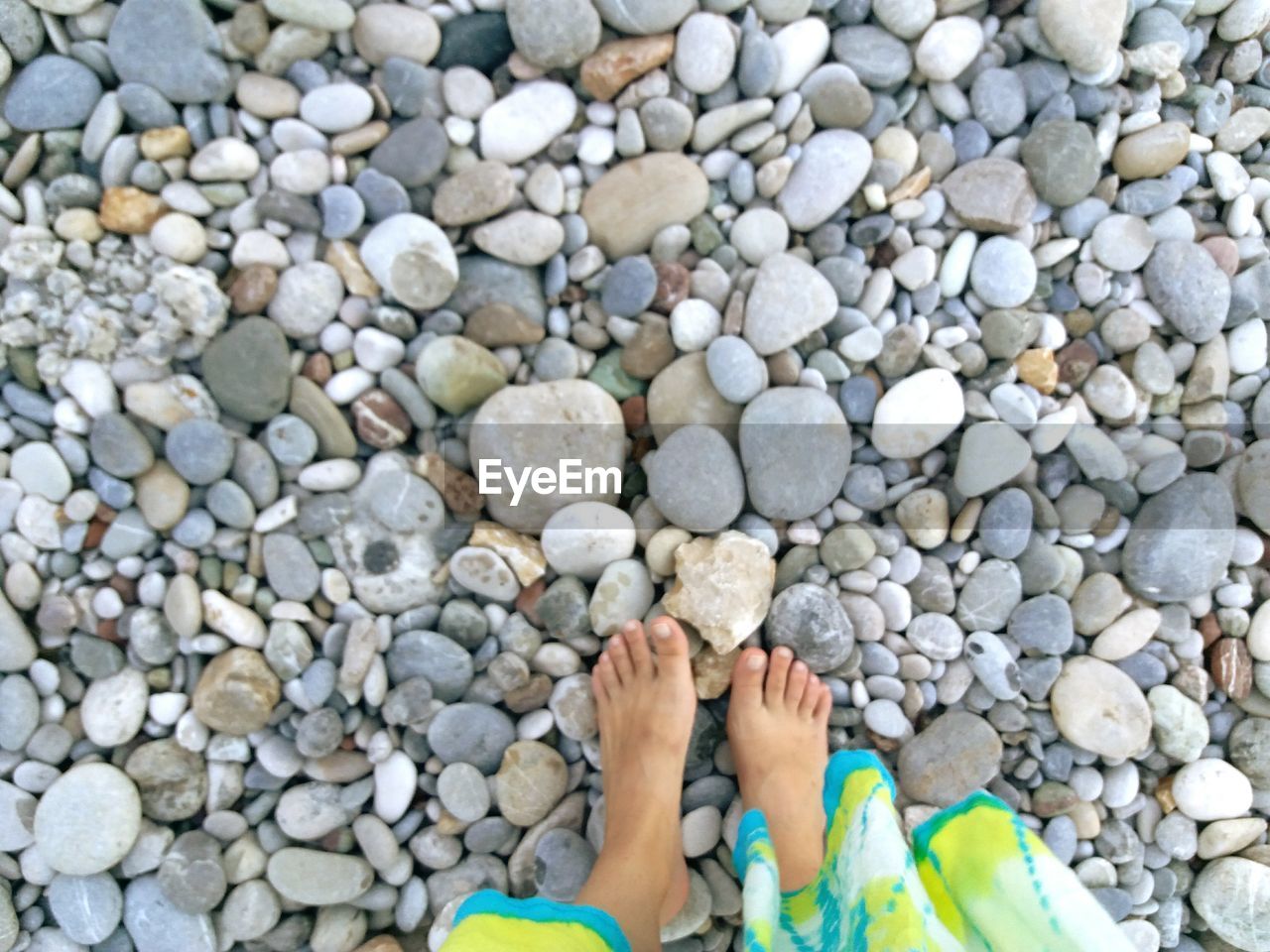 LOW SECTION OF CHILD ON PEBBLES