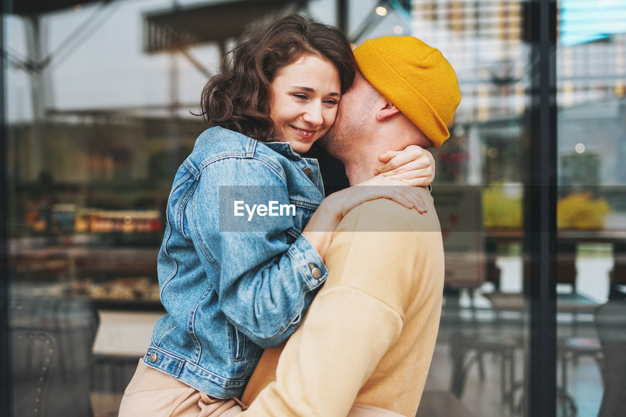 Happy stylish young family couple in love hipsters having fun against glass wall