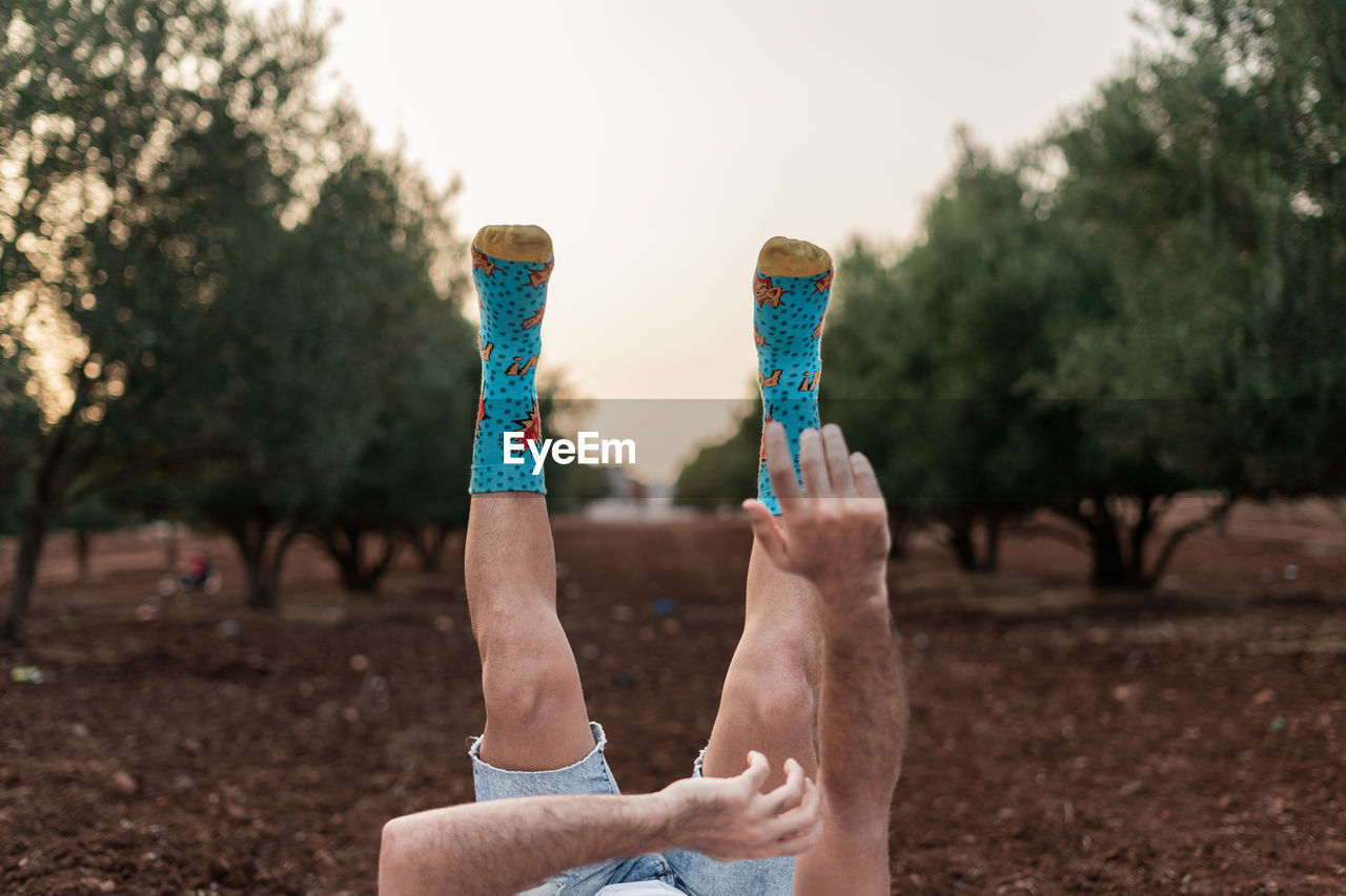 Man's legs and blurry hands up in the air with colourful socks and blue jeans short.