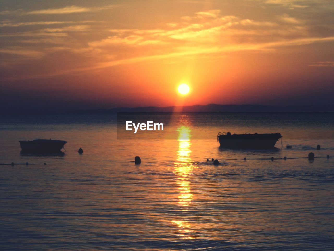 Silhouette boats on sea against sky during sunset