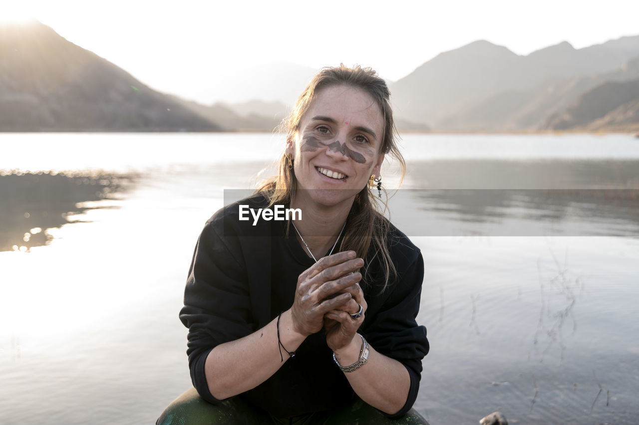 Woman putting mud on hands and face while enjoying outdoors in nature.