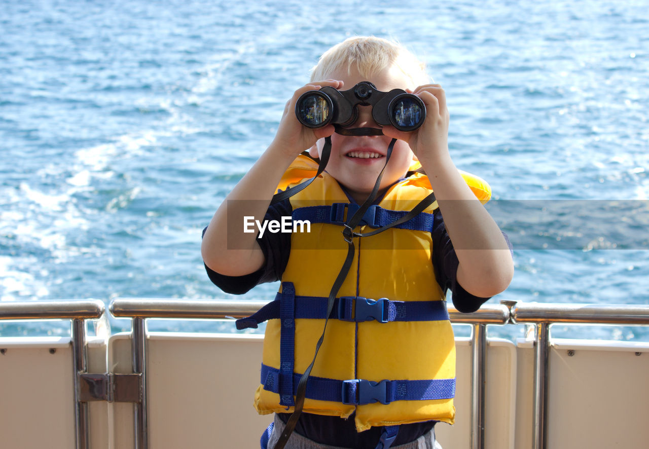 Portrait of boy with binoculars in boat on sea