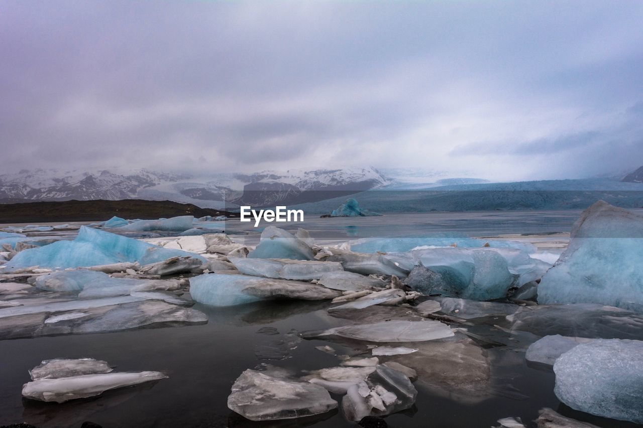 Scenic view of glacier against cloudy sky during winter