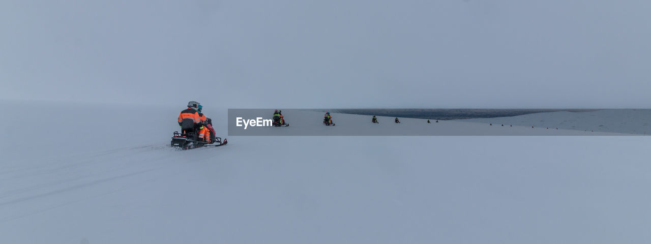 People snowmobiling on snowy glacier