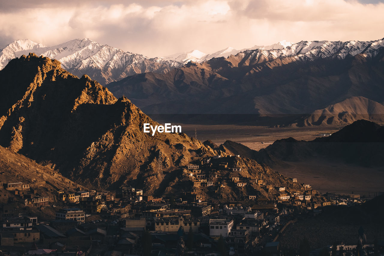 Panoramic view of townscape by mountains against sky