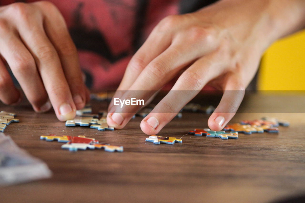 Cropped image of person playing with jigsaw puzzle on table