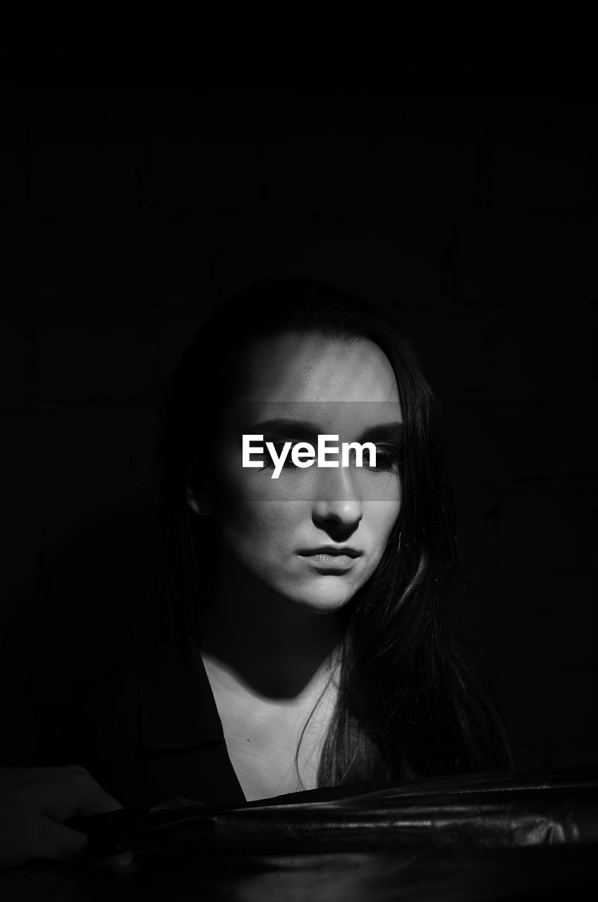 Close-up of thoughtful woman looking away in darkroom