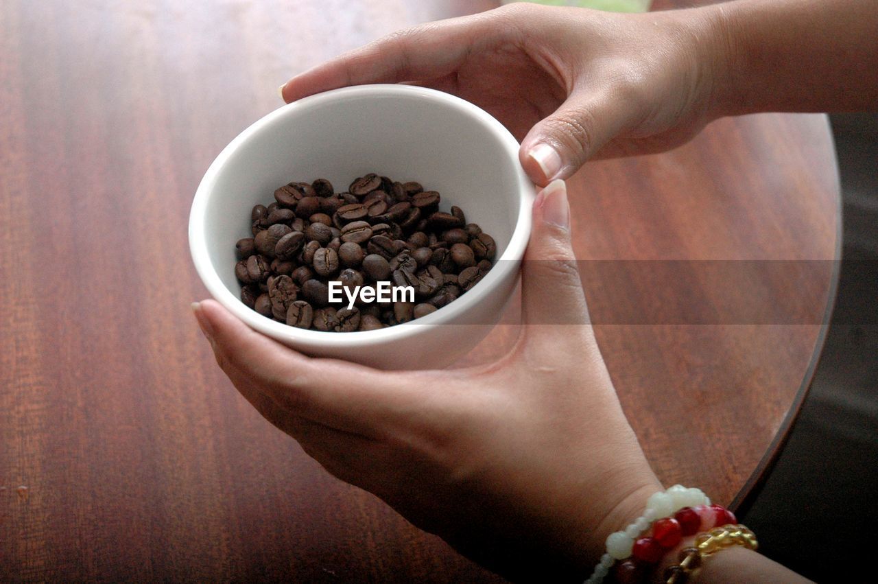 Midsection of woman holding coffee beans in bowl