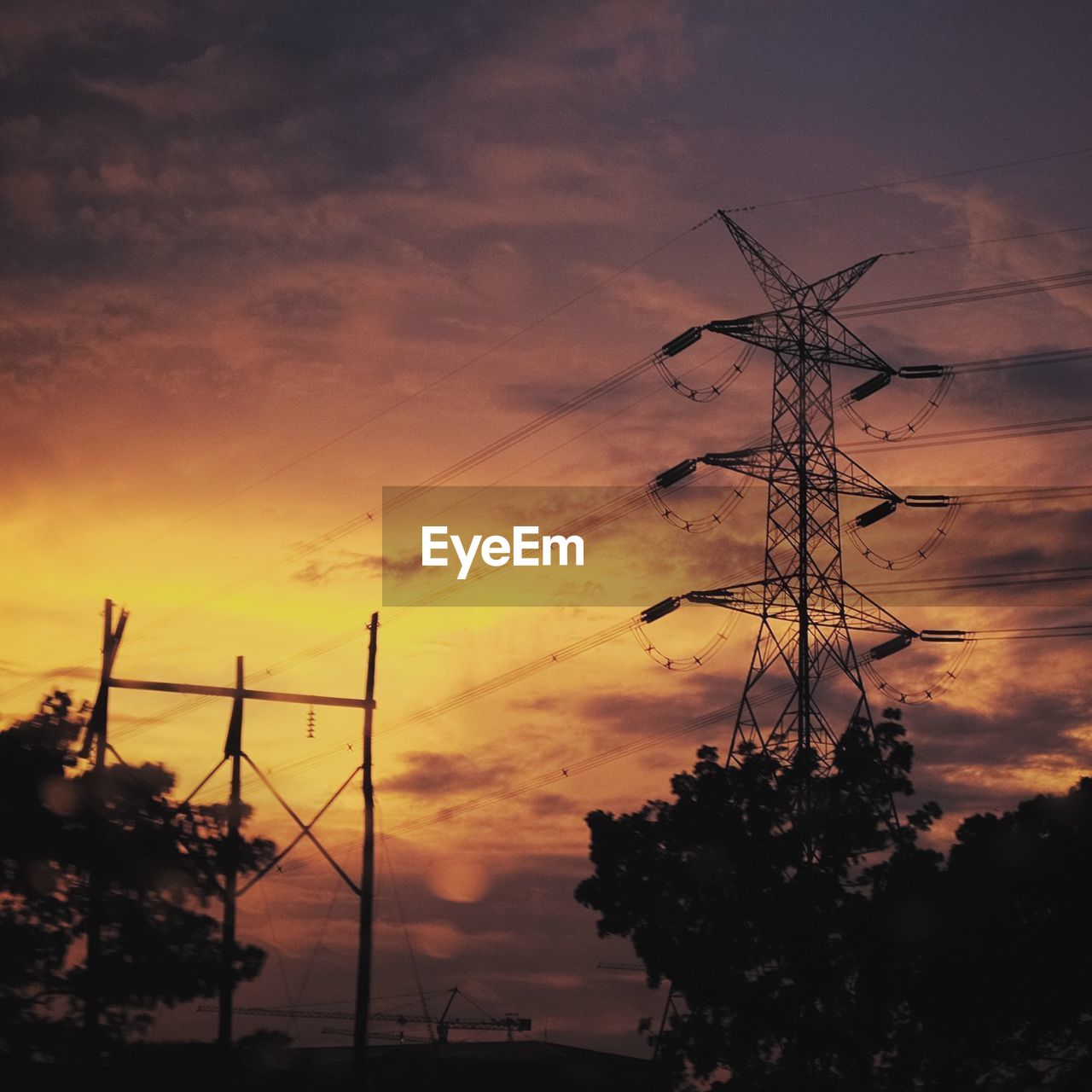 Low angle view of electricity pylon at sunset