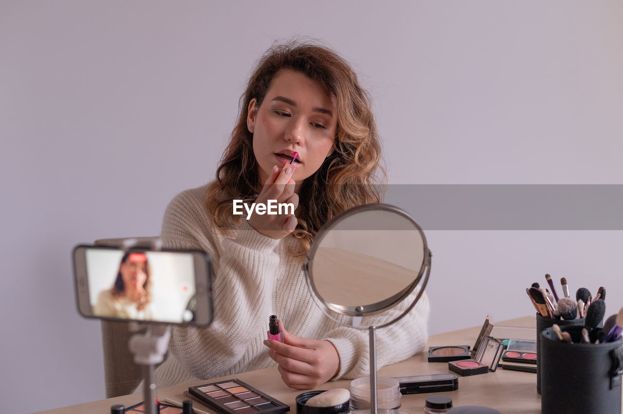 Young woman applying make-up at home