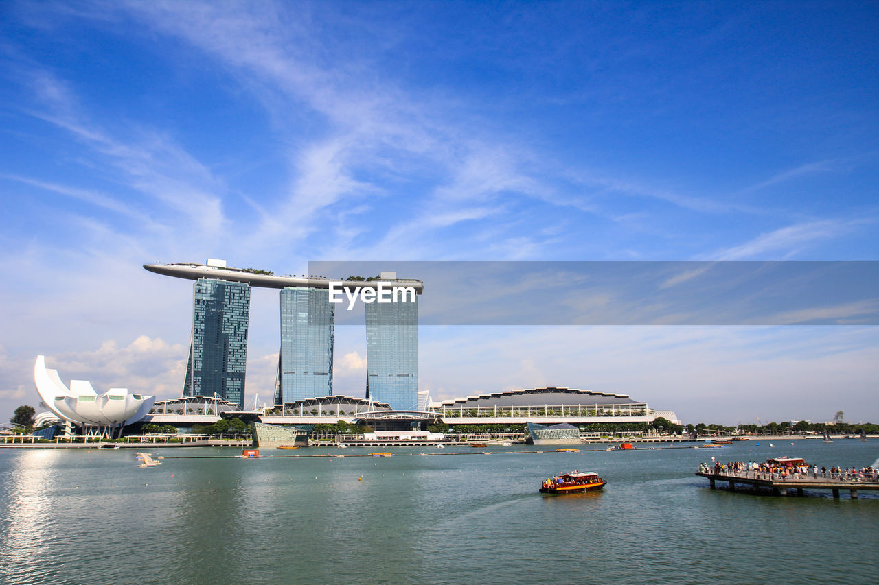 Low angle view of marina bay sands and boats moving on river