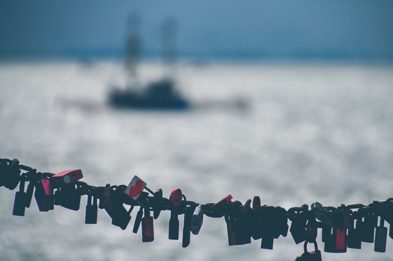 Close-up of love locks with sea in background