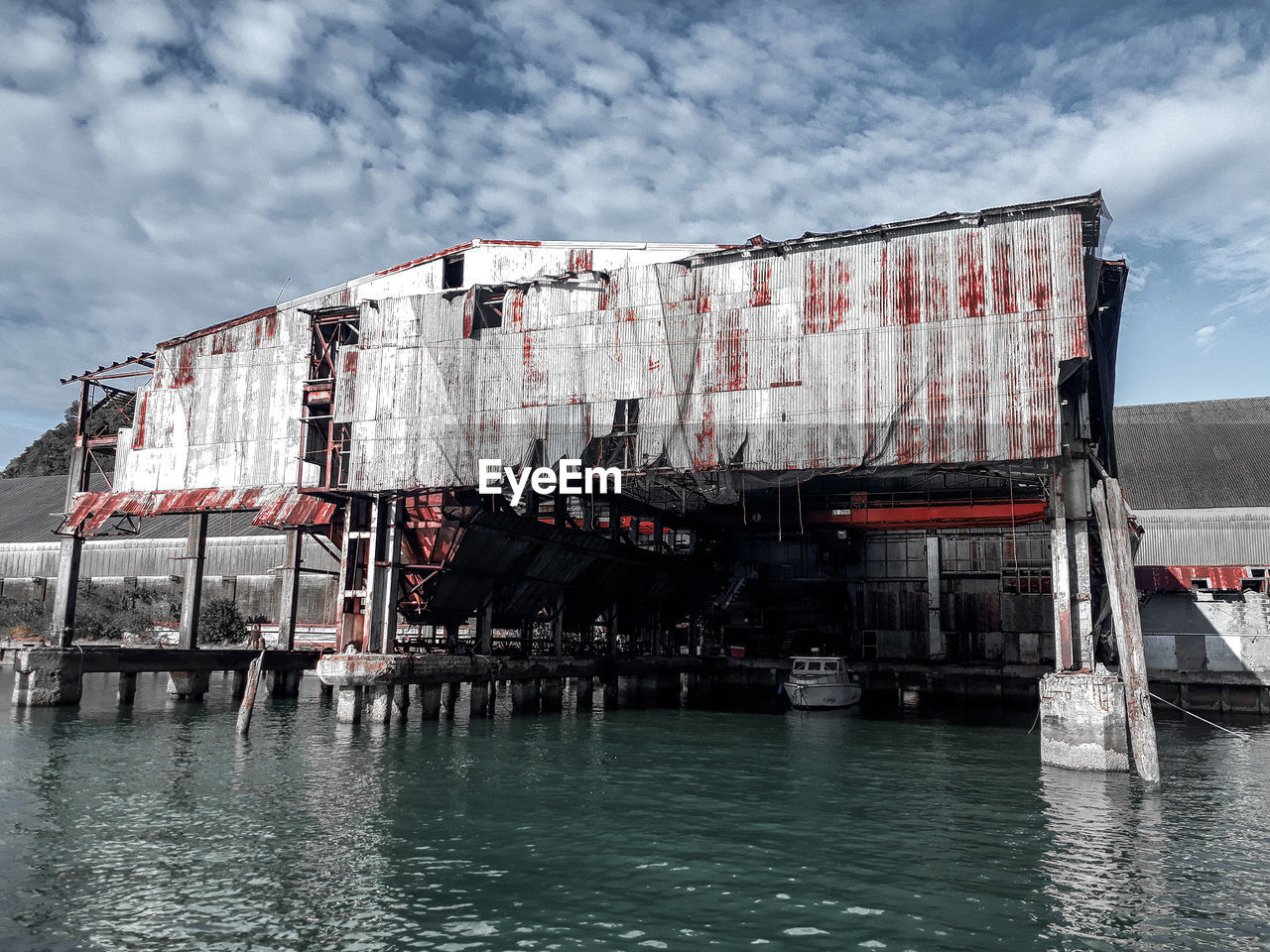 Building by river against sky, old port yard, abandoned port yard