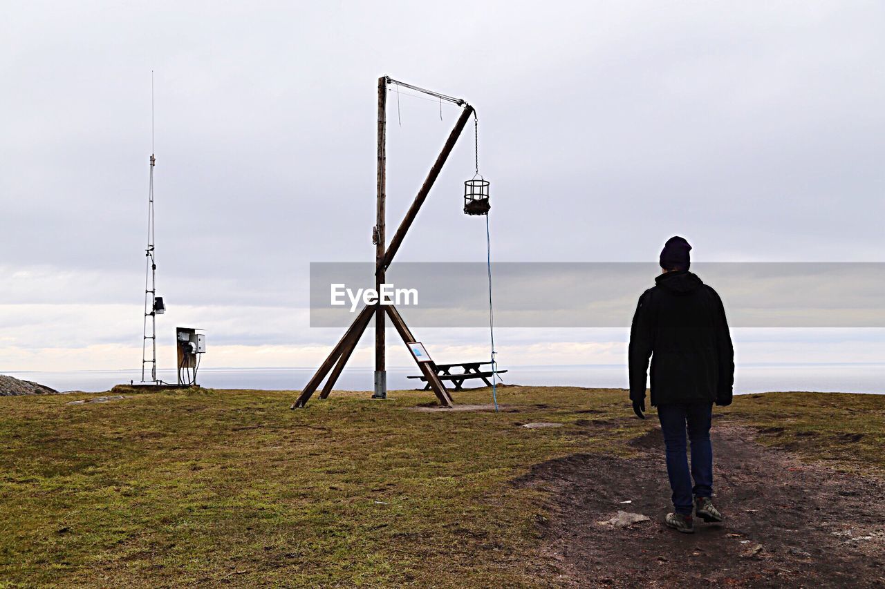 Rear view of person standing by fireplace on field against sky