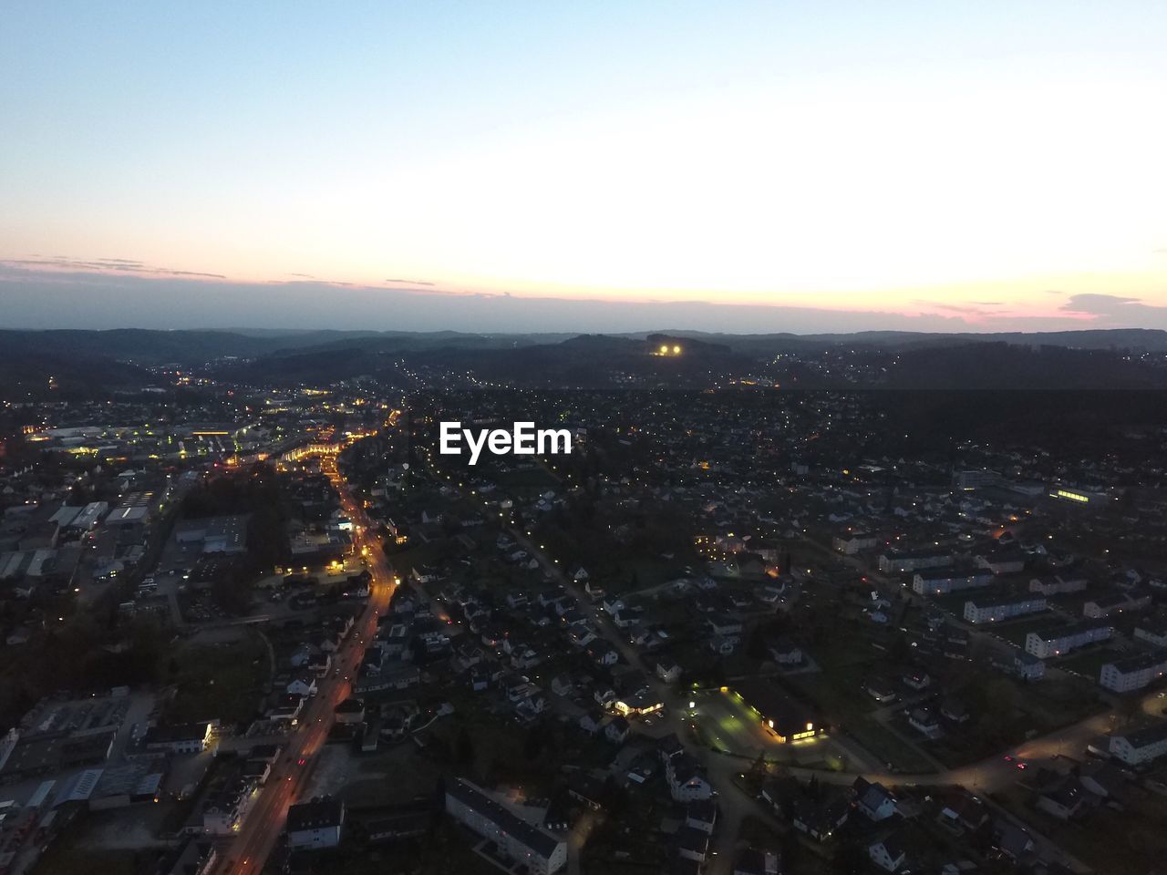 AERIAL VIEW OF ILLUMINATED CITY AT DUSK