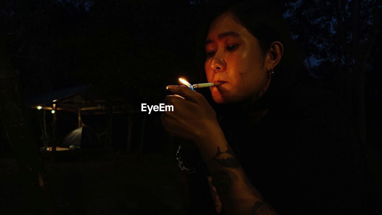 Young woman smoking cigarette at night