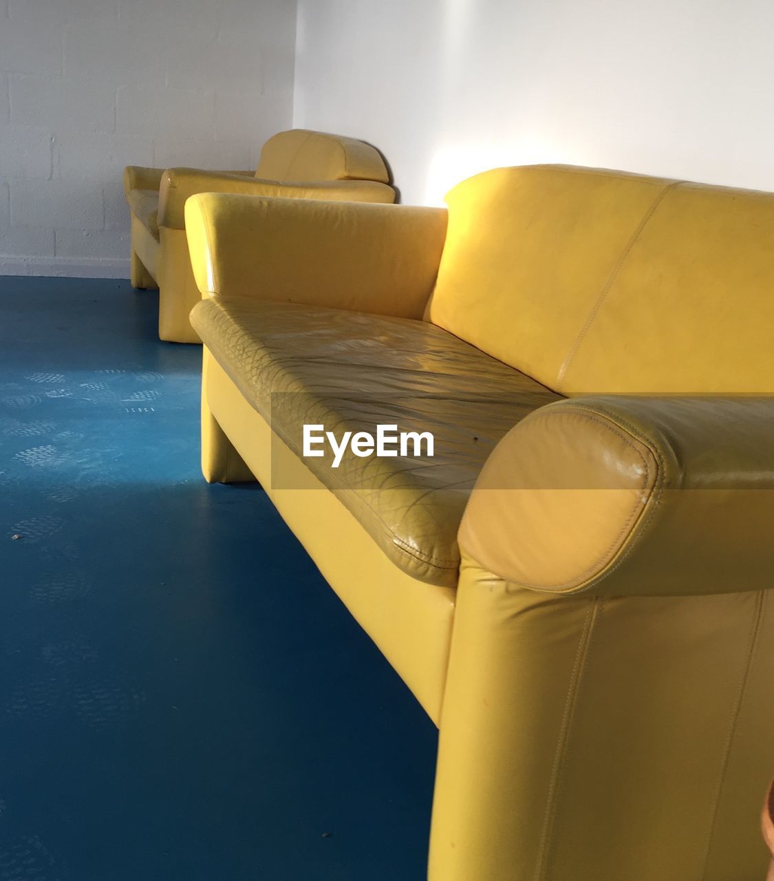 Empty yellow sofa by wall on floor