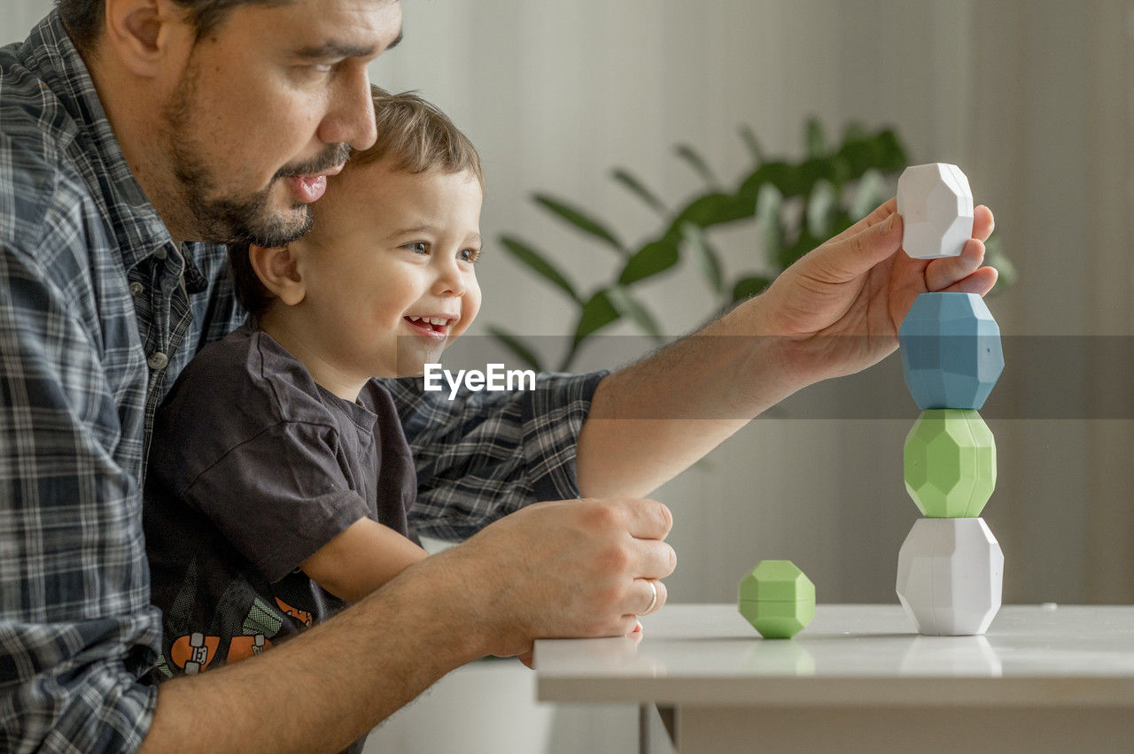 Father and son building tower of blocks at home