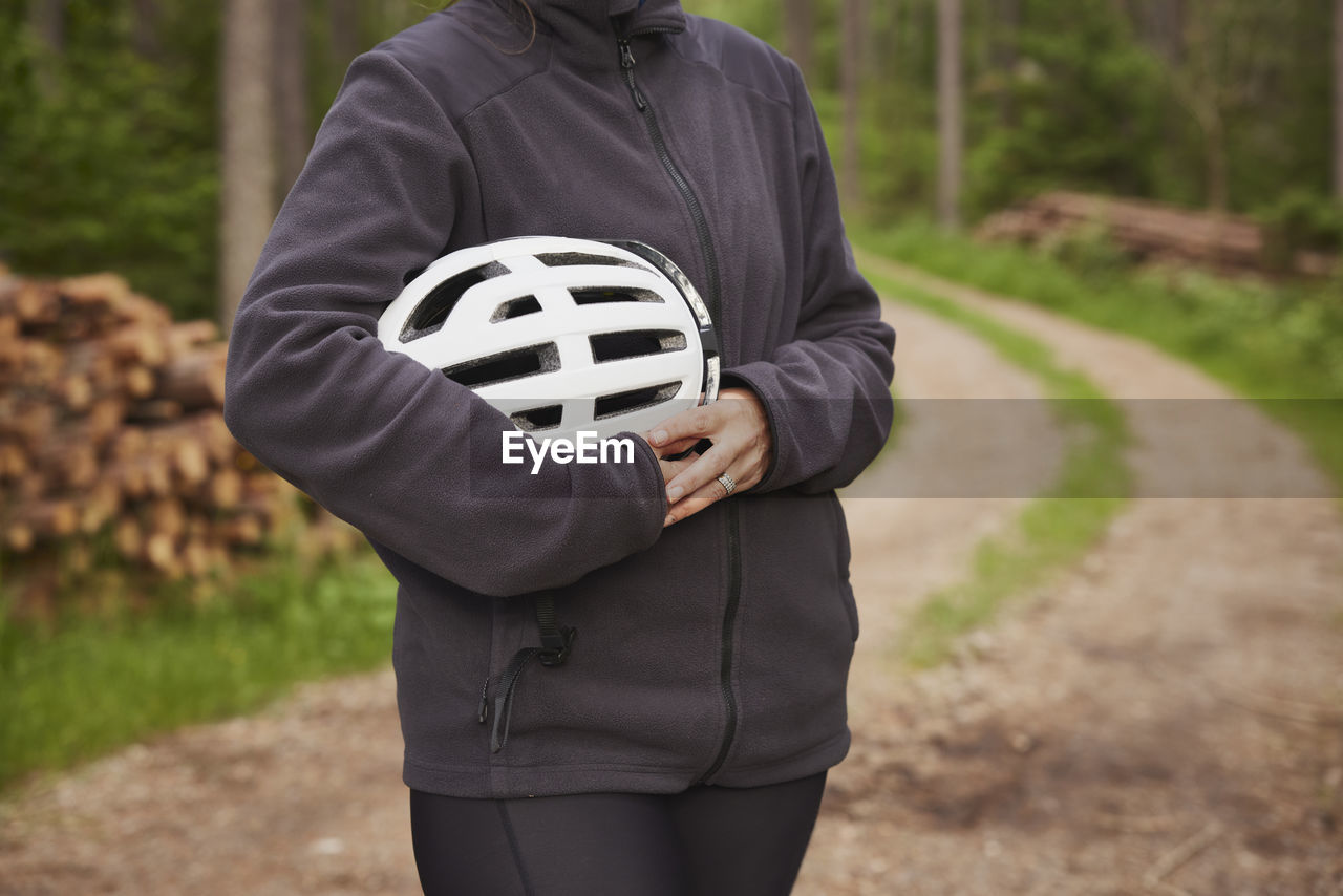 Woman holding bike helmet in forest