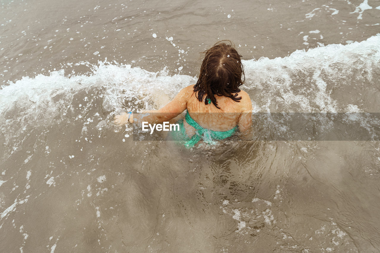 Rear view of girl splashing water in sea
