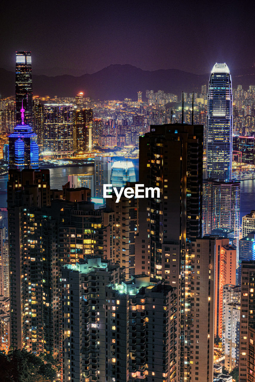 Illuminated buildings in city against sky at night