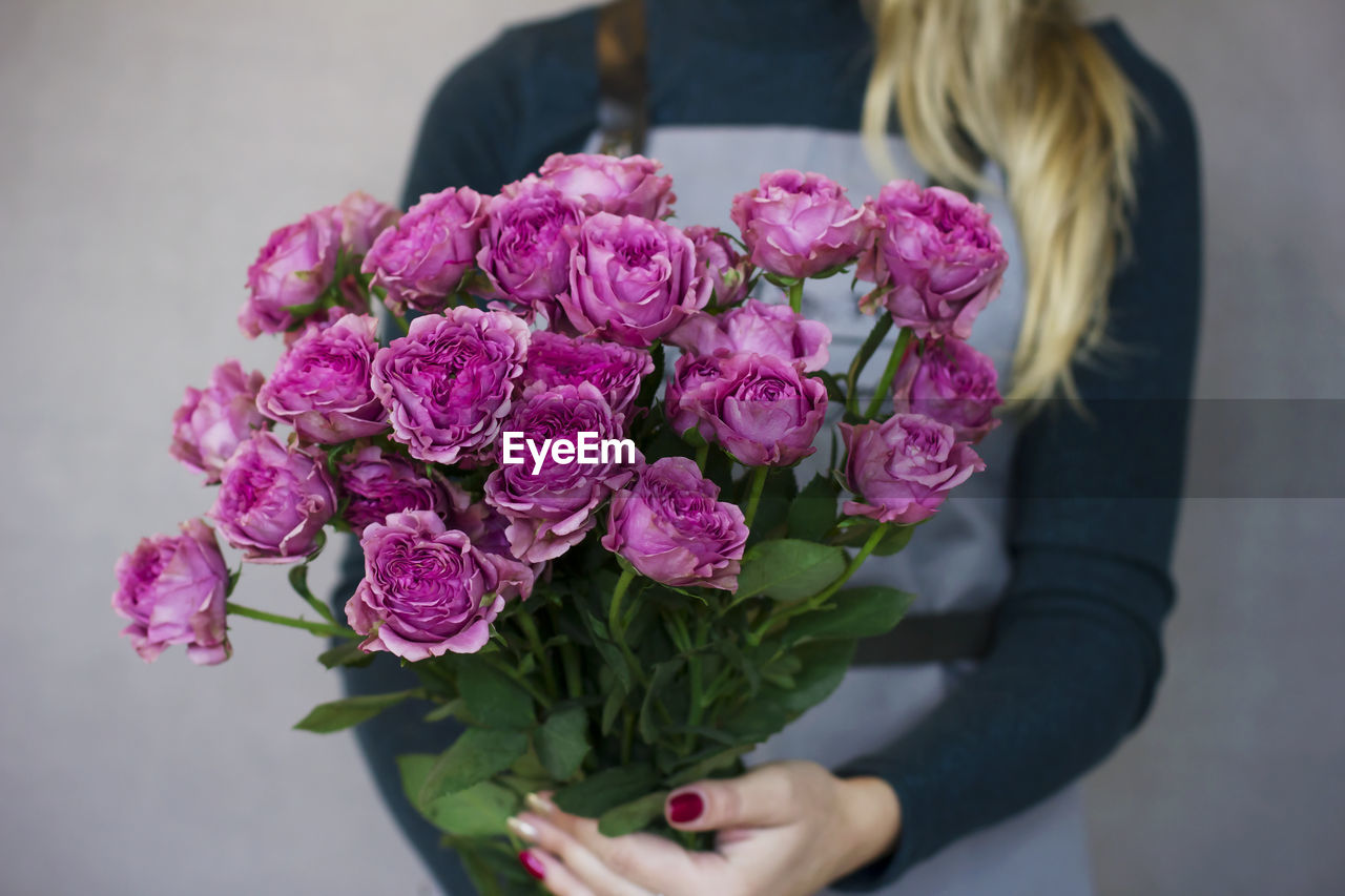 Beautiful young woman holding big bouquet of pink roses