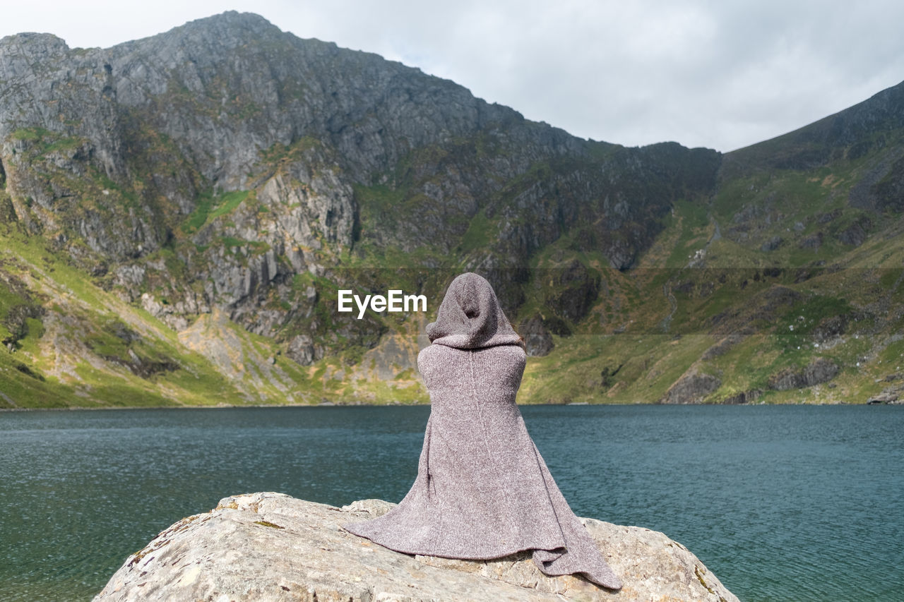 Person and scenic view of lake by rock against sky