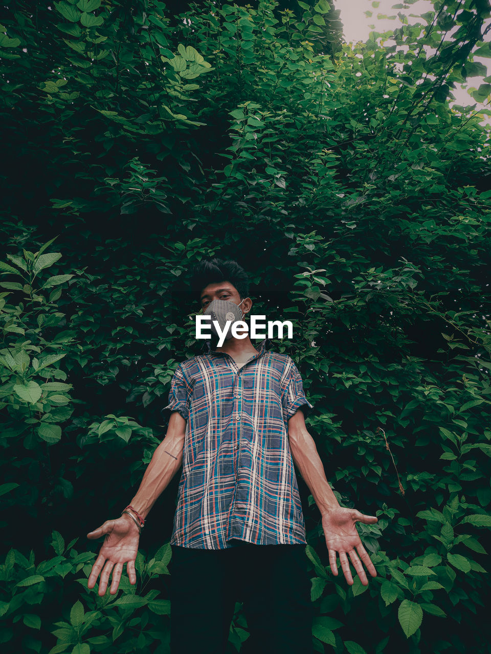 FULL LENGTH PORTRAIT OF YOUNG MAN STANDING AGAINST TREES