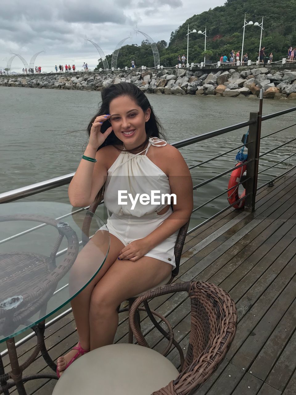 PORTRAIT OF SMILING YOUNG WOMAN SITTING ON BOAT MOORED IN RIVER