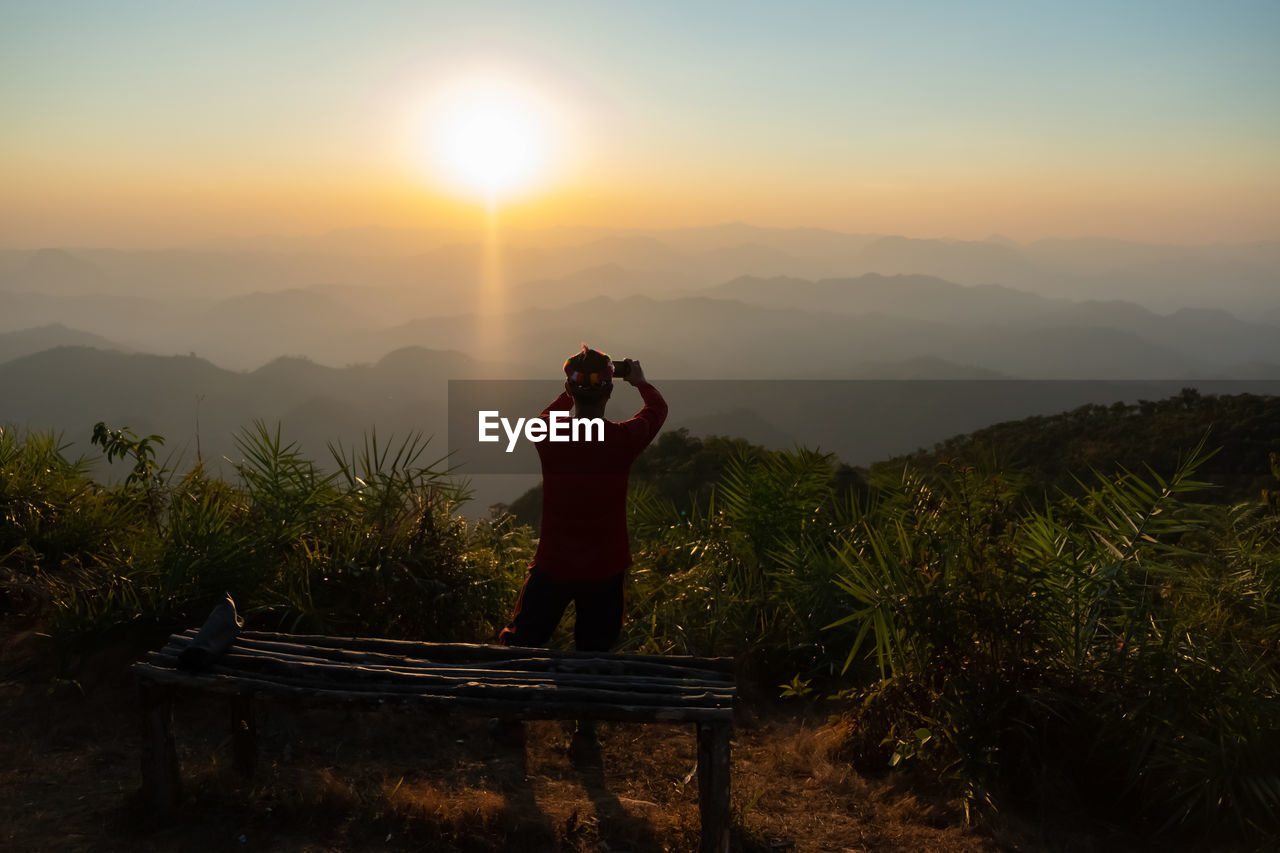 Rear view of man photo graphing during sunset