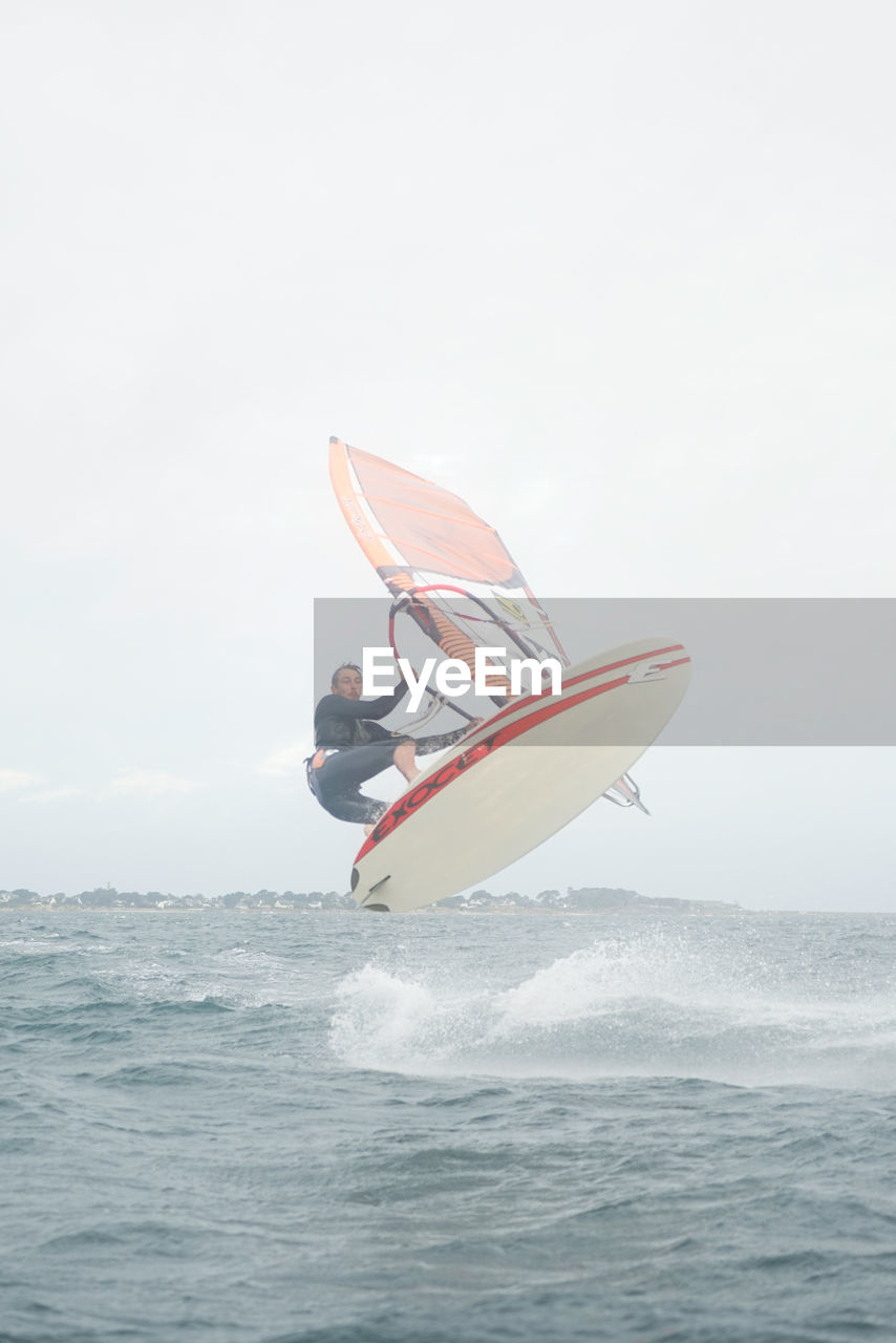 MAN IN SEA AGAINST SKY