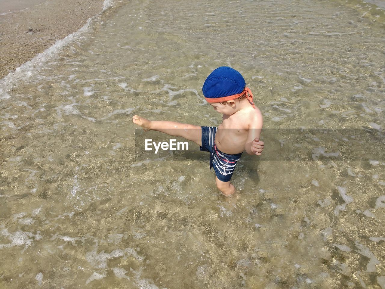 High angle view of boy kicking on shore
