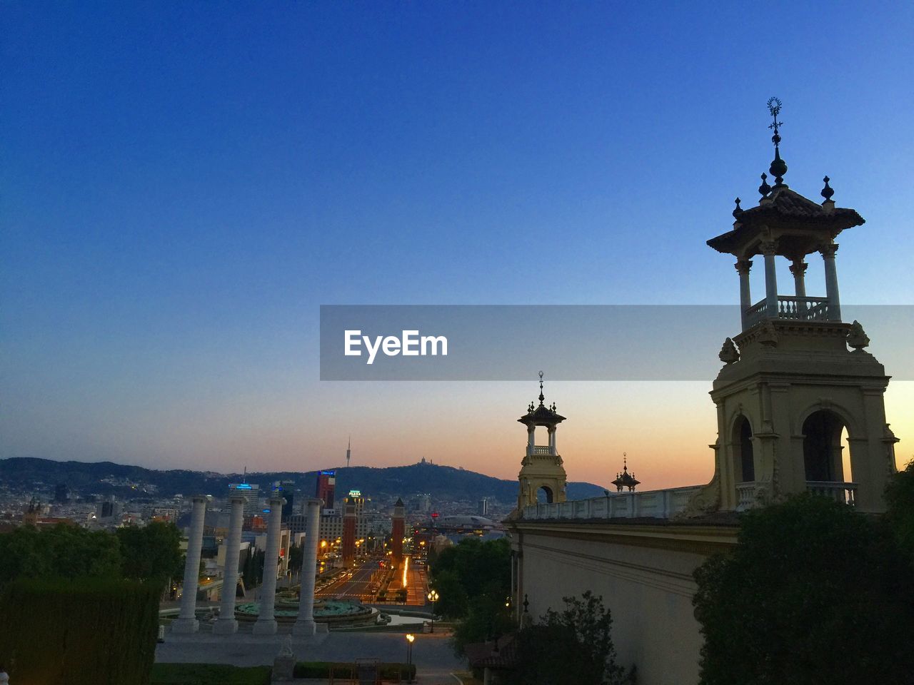 Columns by magic fountain of montjuic against blue sky during sunset