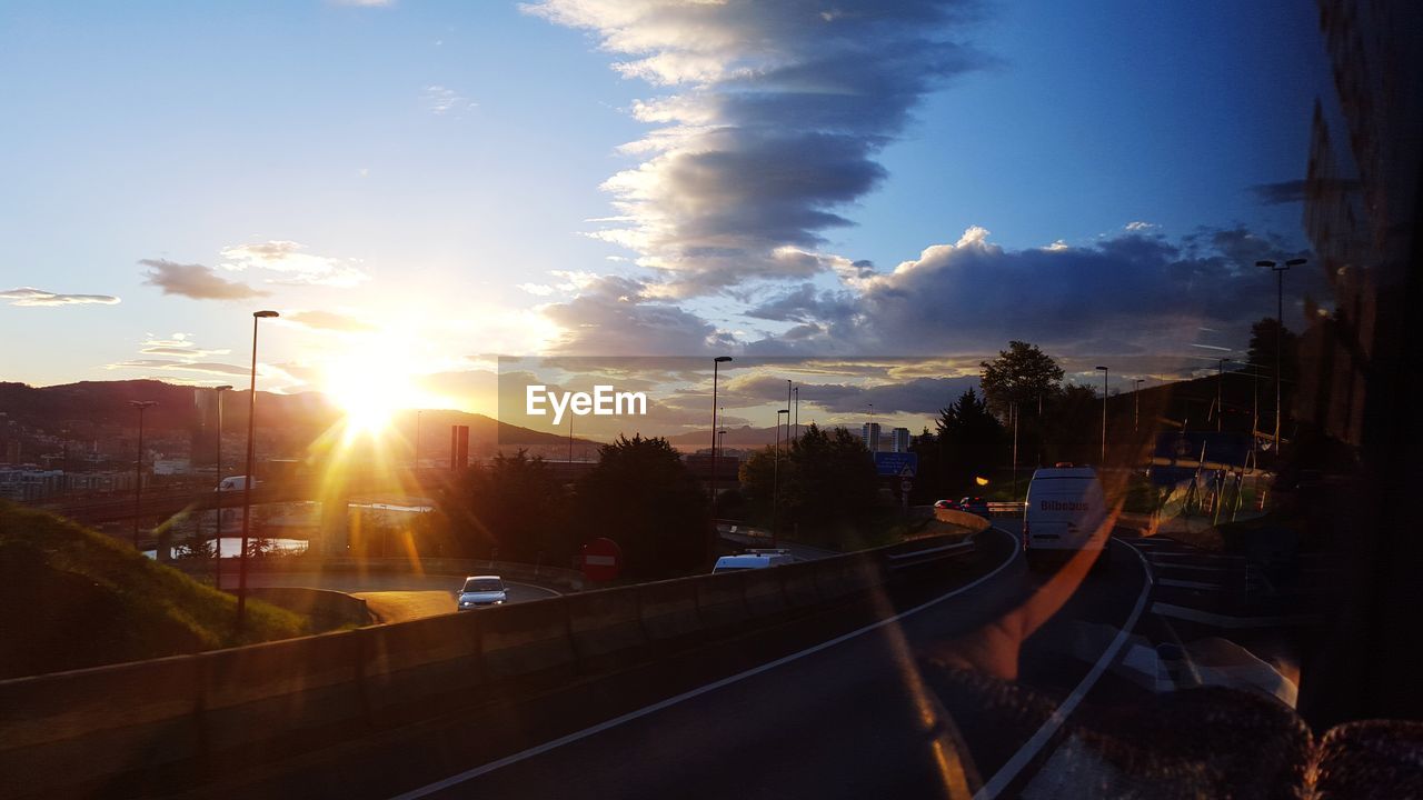 Road in city against sky during sunset