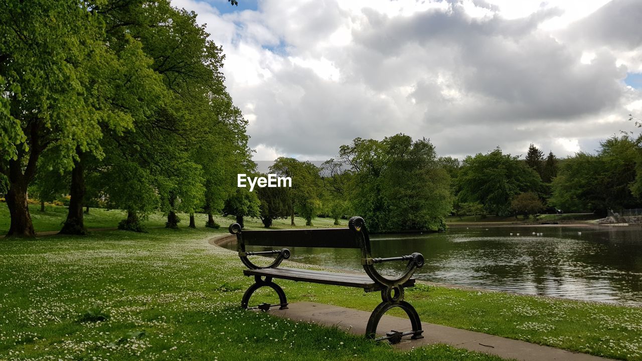 Empty bench in park against sky