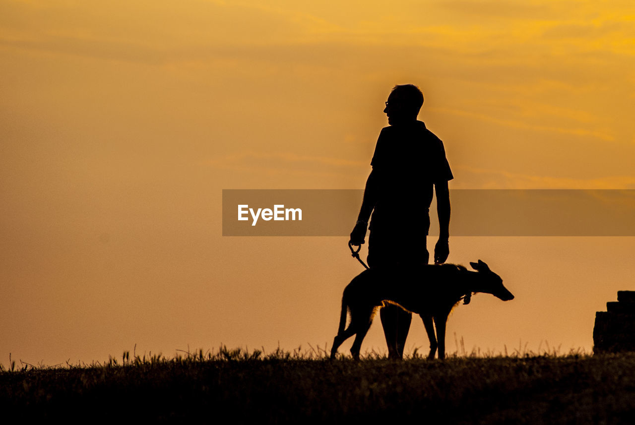 SILHOUETTE MEN ON FIELD DURING SUNSET AGAINST SKY