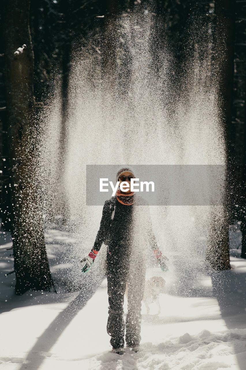 Full length of young woman playing with snow