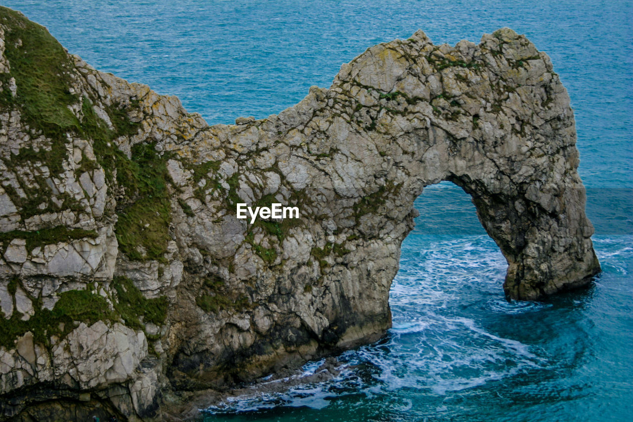 Rock formations by sea against blue sky