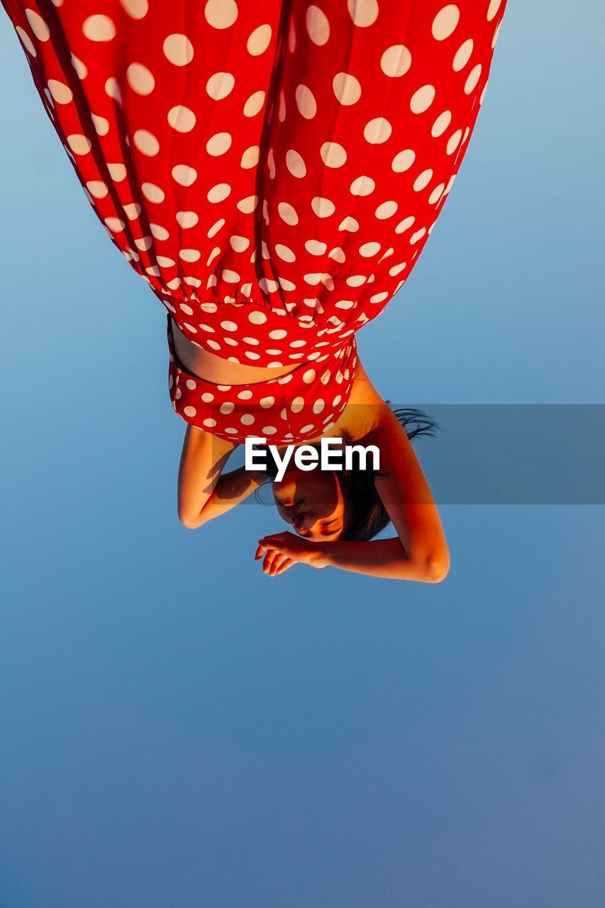 Low angle view of woman standing against clear blue sky