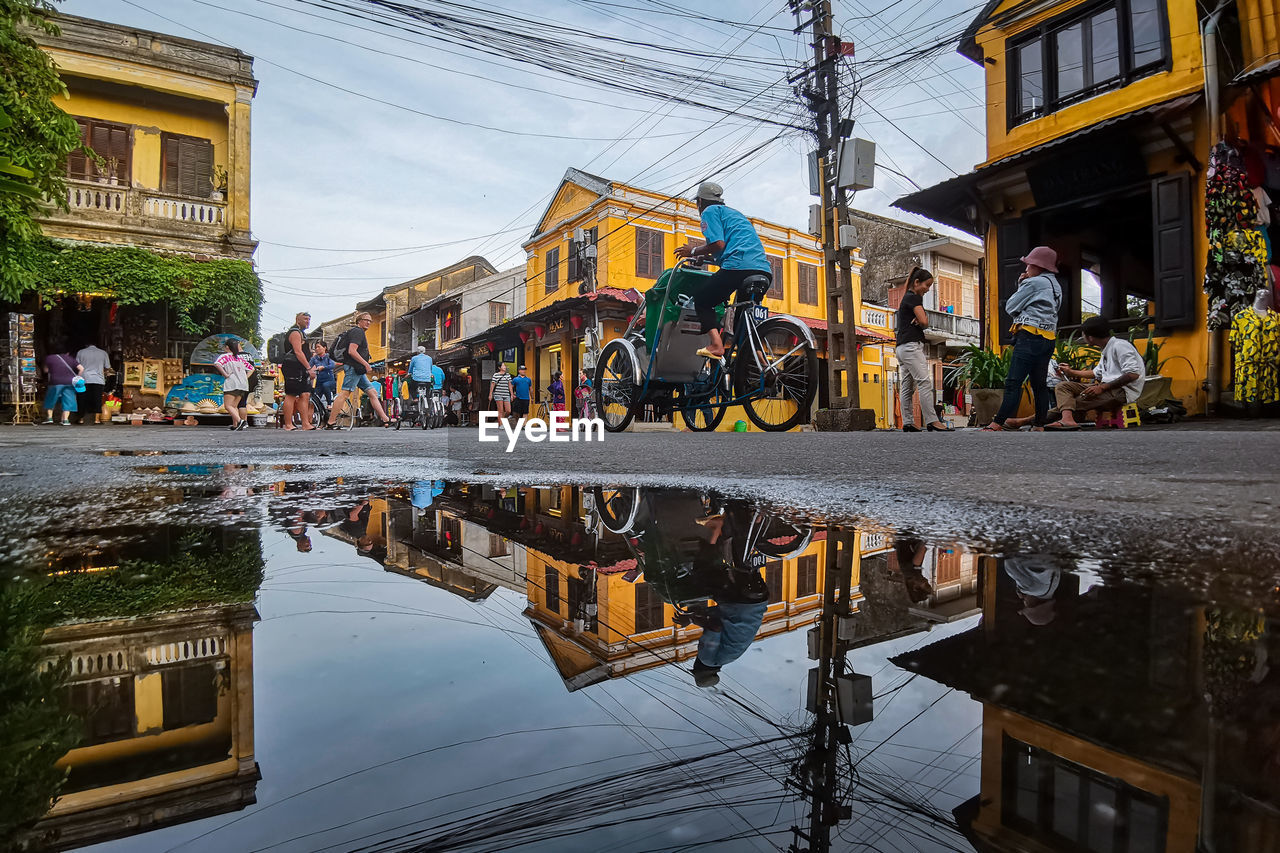 Close-up of puddle while people on street in city