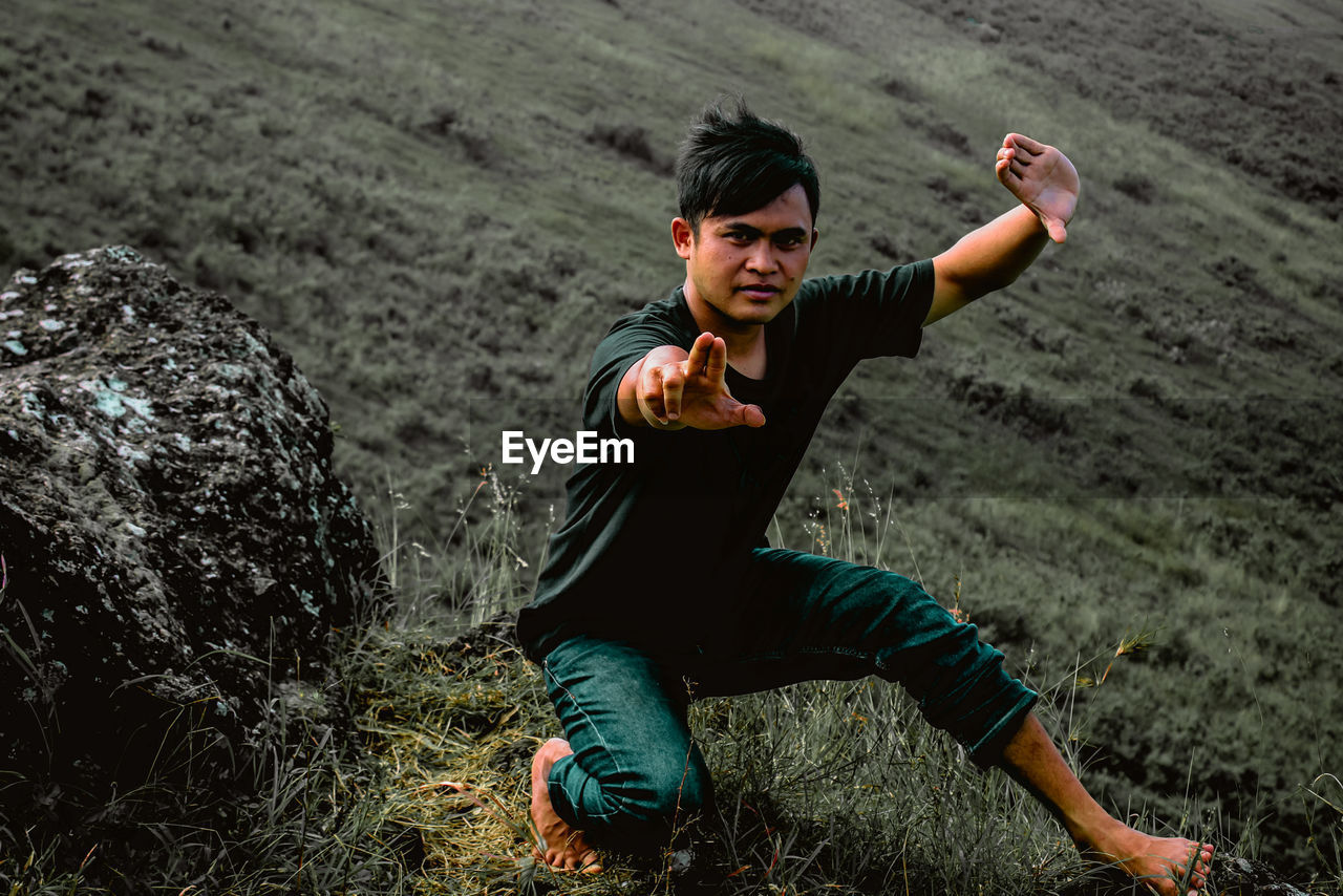 Full length of young man on field, looks like someone's doing a silat exercise move