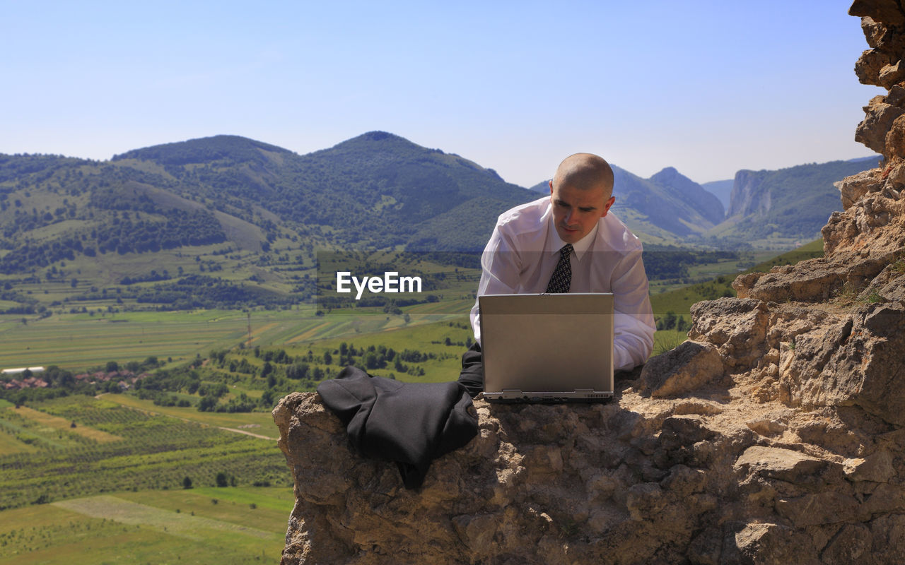 MAN USING MOBILE PHONE ON LANDSCAPE