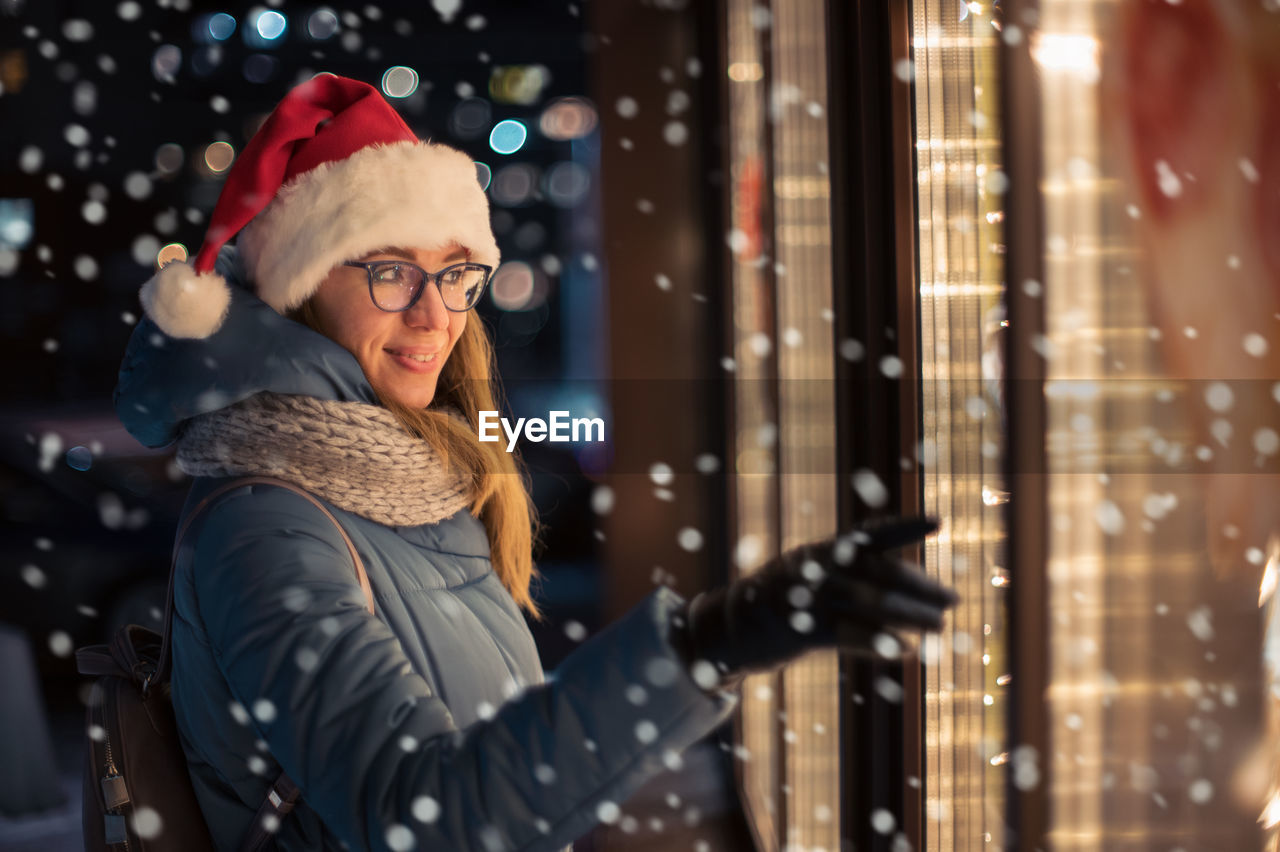 portrait of young woman standing against illuminated city